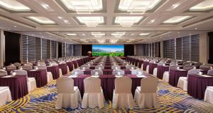 una gran sala de conferencias con filas de sillas y una pantalla en Huachen International Hotel en Hangzhou