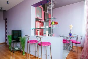 un bar con taburetes rosas y TV en una habitación en Vip-kvartira Kiseleva, en Minsk