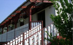 a white picket fence in front of a house at Relax Apartmanok in Zalakaros