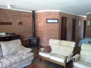a living room with two couches and a brick wall at Busselton Beachfront in Busselton
