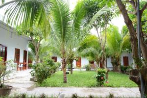 a courtyard with palm trees in front of a building at Diem Lien Guesthouse in Mui Ne