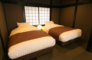 two beds in a room with a window at Hosta Umekoji Miyabi in Kyoto