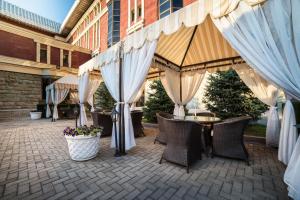 a patio with tables and chairs and white umbrellas at The Dostyk Hotel in Almaty