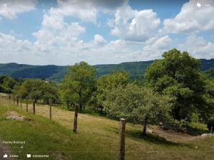 een hek in een veld met bomen en bergen bij La Ferme de Là-haut B&B in Le Haut-du-Them