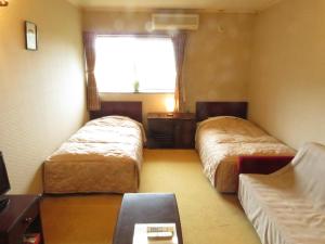 una camera d'albergo con due letti e una finestra di Nikko Pension L'escale a Nikko