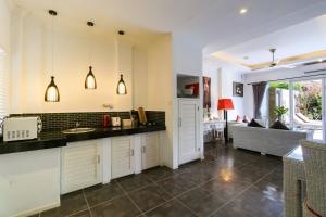 a kitchen with white cabinets and a living room at Aleesha Villas and Suites in Sanur