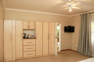 a kitchen with wooden cabinets and a ceiling fan at Poetry Guestrooms in Vryburg
