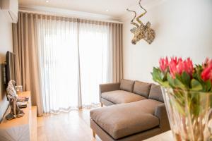 een woonkamer met een bank en een vaas met rode bloemen bij Collection Luxury Accommodation - 7 On Murray 2 En-suite Bedroom Apartment in Stellenbosch