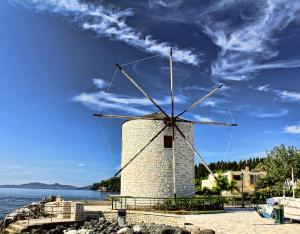 a windmill on the shore of a body of water at The Olive Tree House in Kompítsion