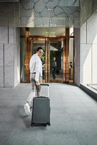 a man with a suitcase in front of a building at Silks Club in Kaohsiung