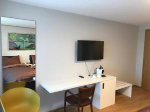 Cette chambre comprend un bureau, une télévision et un lit. dans l'établissement Schüür Restaurant & Kultur, à Steffisburg