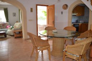 eine Küche und ein Wohnzimmer mit einem Glastisch und Stühlen in der Unterkunft Libertad LOCDENIA in Els Poblets