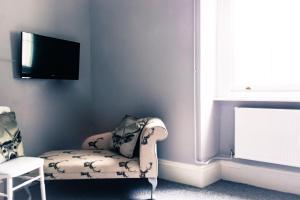 a room with a chair and a tv on a wall at The Old Down Inn in Radstock