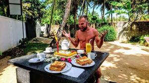 a man sitting at a table with food on it at Midigama Holiday Inn in Midigama East