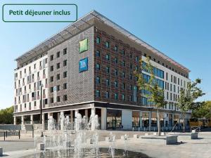 um grande edifício com uma fonte em frente em ibis Styles Nimes Gare Centre em Nîmes
