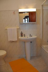 W łazience znajduje się umywalka, toaleta i lustro. w obiekcie Apartamentos Campos 0 w mieście Porto Covo