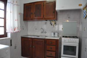 a kitchen with wooden cabinets and a white stove top oven at Apartamentos Campos 0 in Porto Covo