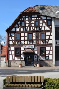 ein großes Holzgebäude mit einer Bank davor in der Unterkunft Schützenhof in Neuhof