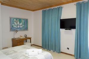 a bedroom with blue curtains and a bed and a tv at Tuscany Vryburg in Vryburg