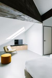 a bedroom with a bed and a yellow chair at TRUST Hotel in Beveren