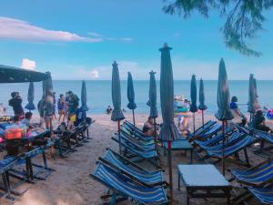 a group of people sitting in chairs on a beach with umbrellas at Sam Resort Chaam in Cha Am