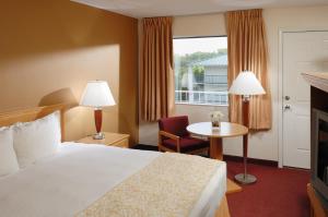 布蘭森的住宿－低語山汽車旅館，酒店客房设有床、桌子和窗户。