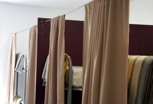 a mirror in a bedroom with curtains and a chair at Albergue Santiago Apostol in Logroño