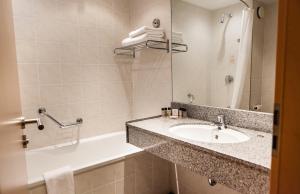 a bathroom with a sink, mirror, and bathtub at Clayton Hotel, Leeds in Leeds