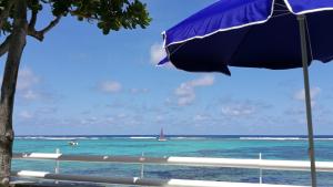 a blue umbrella on the beach with a sailboat in the ocean at Blue Beryl Guest House in Blue Bay