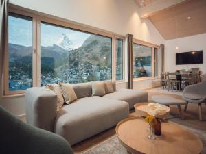 a living room with a couch and a view of a mountain at OVERLOOK Lodge by CERVO Zermatt in Zermatt