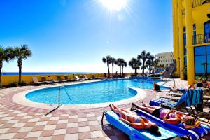 um grupo de pessoas deitadas em espreguiçadeiras junto a uma piscina em The Oasis at Orange Beach Condos by Hosteeva em Orange Beach