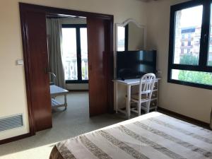 a bedroom with a bed and a desk with a television at Hotel Magallón in Caspe