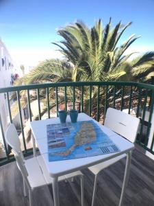 a white table and chairs on a balcony with palm trees at Apartment Enjoy Corralejo in Corralejo