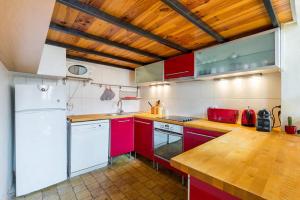 kuchnia z czerwonymi szafkami i drewnianym sufitem w obiekcie Loft coeur du Vieux Lyon w mieście Lyon