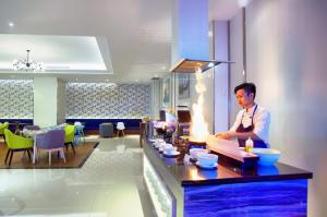 a man standing behind a counter in a restaurant at Golden Tulip Essential Makassar in Makassar