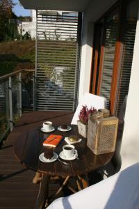 una mesa de madera con tazas y platos de comida en el balcón en Sunshine Apartament Sopot, en Sopot