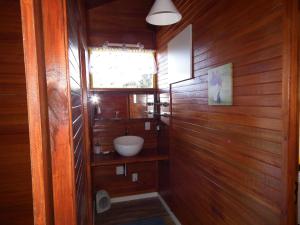 uma casa de banho com um lavatório numa parede de madeira em Chale dos Beija Flores em Gramado