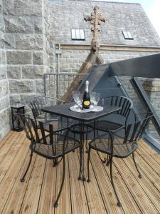 una mesa negra y sillas en un balcón con una botella de vino en Lovat Loch Ness Apartment with private roof terrace en Fort Augustus