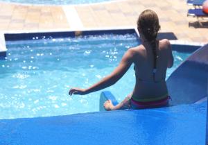 una mujer en traje de baño sentada en una piscina en Mediterraneo Hotel, en Hersonissos