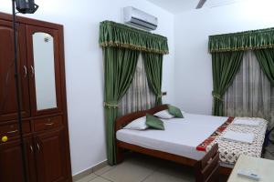 1 dormitorio con 1 cama con cortinas verdes en kevins Placid Homestay en Kochi