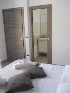 a bedroom with a white bed with a large mirror at Summer Beach Rooms in Fontane Bianche
