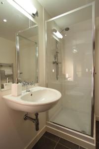 La salle de bains blanche est pourvue d'un lavabo et d'une douche. dans l'établissement Lovat Loch Ness Apartment with private roof terrace, à Fort Augustus