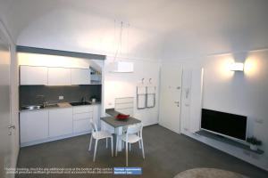 a kitchen with white cabinets and a table and chairs at G30 Finalborgo Lodging'n Bike Box in Finale Ligure