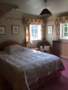 a bedroom with a bed and a chair and windows at Lime Trees Farm in Bicester