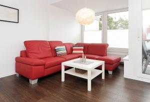 ein Wohnzimmer mit einem roten Sofa und einem Tisch in der Unterkunft Haus Kunterbunt in Bensersiel