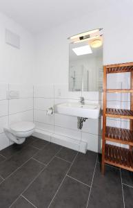 een witte badkamer met een toilet en een wastafel bij Haus Kunterbunt in Bensersiel