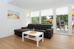 ein Wohnzimmer mit einem schwarzen Sofa und einem Tisch in der Unterkunft Haus Kunterbunt in Bensersiel