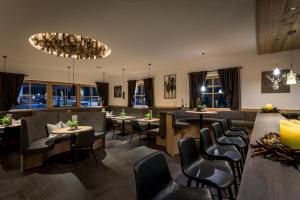a restaurant with tables and chairs and windows at Hotel La Fradora - Dolomites Hotel in San Cassiano