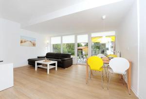 a living room with a table and yellow chairs at Haus Kunterbunt in Bensersiel