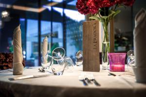 una mesa con copas de vino y un jarrón de flores en Hotel La Fradora - Dolomites Hotel, en San Cassiano